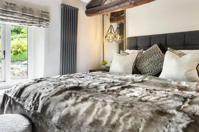 a bedroom with a large bed and a window at Coronation Family Cottage, Modernised 200-Year-Old Lake District Cottage with Private Hot Tub and Parking - Ridgestone in Lindale