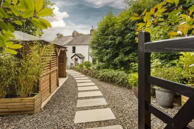 a garden path with a fence and a house at Coronation Family Cottage, Modernised 200-Year-Old Lake District Cottage with Private Hot Tub and Parking - Ridgestone in Lindale
