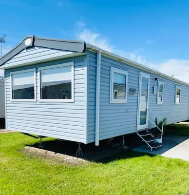 a blue tiny house sitting on the grass at Haven, Cala Gran caravan park, privately owned in Blackpool