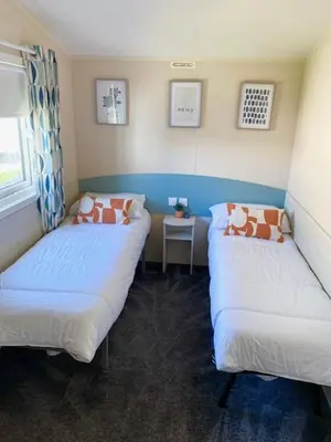 two twin beds in a room with a window at Haven, Cala Gran caravan park, privately owned in Blackpool
