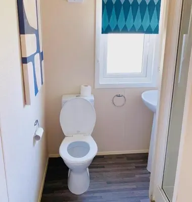 a bathroom with a white toilet and a window at Haven, Cala Gran caravan park, privately owned in Blackpool
