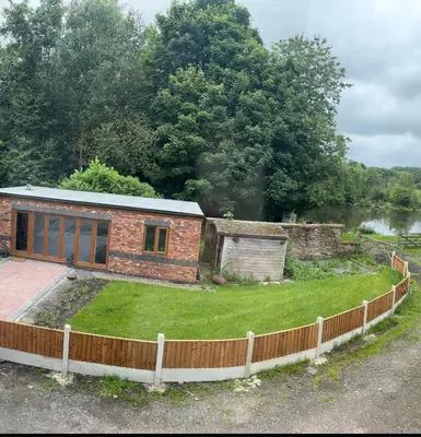 a small brick house with a fence around it at Goldie's Retreat in Blackrod