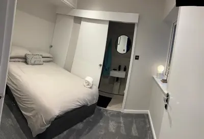 a small bedroom with a bed and a mirror at Goldie's Retreat in Blackrod