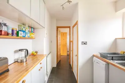 a kitchen with white cabinets and a wooden counter top at Cosy Single Room l Smart TV l 5 Minute Walk from Train Station in Bolton