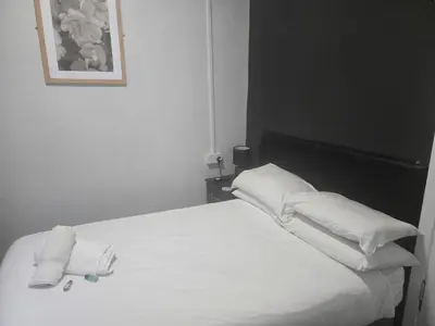 a black and white photo of a bed with white pillows at Peek-a-Booze - Budget Hotel - Adults Only in Blackpool