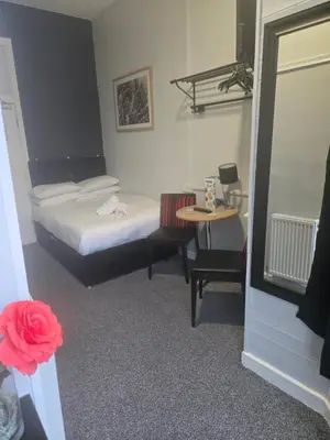 a small bedroom with a bed and a table at Peek-a-Booze - Budget Hotel - Adults Only in Blackpool