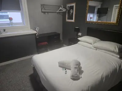 a hotel room with a large white bed and a mirror at Peek-a-Booze - Budget Hotel - Adults Only in Blackpool