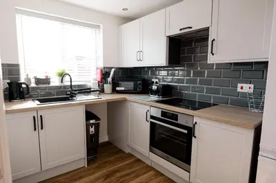 a kitchen with white cabinets and black appliances at Stylish Modern Apartment in Blackpool with Parking in Blackpool
