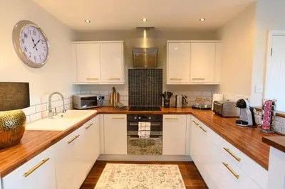 a kitchen with white cabinets and a clock on the wall at Stunning Liverpool City Location with River View and parking space included in Liverpool