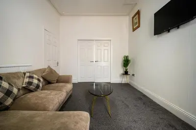 a living room with a couch and a glass table at Seaside - House - Sleeps 10 - Parking - Garden in Blackpool