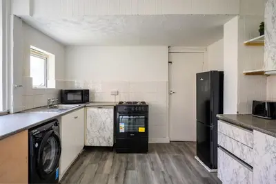 a kitchen with a black refrigerator and a dishwasher at Seaside - House - Sleeps 10 - Parking - Garden in Blackpool