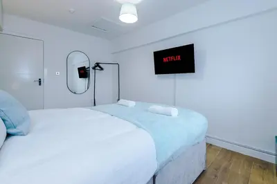 a white room with a bed and a tv on the wall at #6 - Vibrant apartment in City Centre - Sleeps 7 - Exclusive offers at a-kapartments in Liverpool