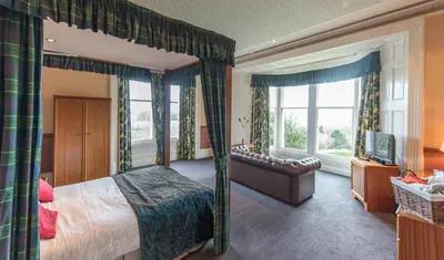 a bedroom with a bed and a couch and windows at Cumbria Grand Hotel in Grange Over Sands
