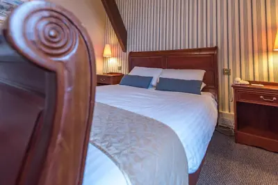 a bedroom with a large bed with blue pillows at Cumbria Grand Hotel in Grange Over Sands
