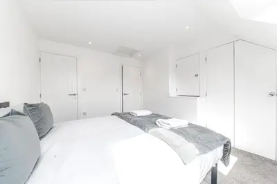 a white bedroom with a bed and white cabinets at Barrow Central 3 Bedroom House in Roose