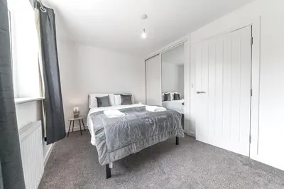 a white bedroom with a bed and a mirror at Barrow Central 3 Bedroom House in Roose