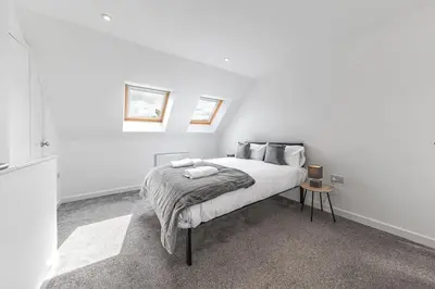 a white bedroom with a bed and a table at Barrow Central 3 Bedroom House in Roose