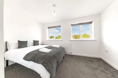 a white bedroom with a large bed and two windows at Barrow Central 3 Bedroom House in Roose