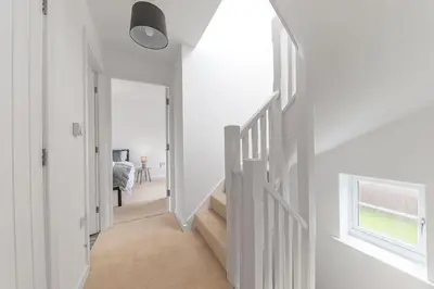a white hallway with stairs and a window at Barrow- 4 bedroom Detached House in Roose
