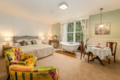 a bedroom with a bed and a tub and a chair at Grange Manor in Grange Over Sands