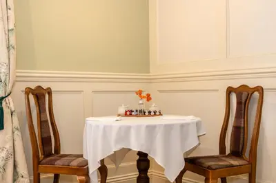a table with two chairs and a table with a cake on it at Grange Manor in Grange Over Sands