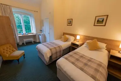 a hotel room with two beds and a chair at Ashton Hall at Lancaster Golf Club in Lancaster