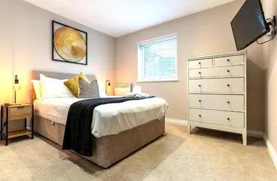 a bedroom with a bed with a dresser and a television at The Slipway Cabins with Hottub in Burscough