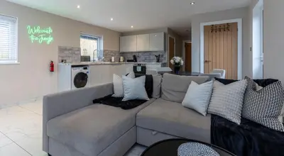 a living room with a couch and a kitchen at The Slipway Cabins with Hottub in Burscough