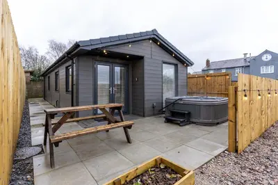 a small shed with a bench and a hot tub at The Slipway Cabins with Hottub in Burscough