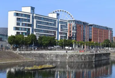 a large building with a ferris wheel in front of a river at Dockside Aparthotel, Best Western Signature Collection in Liverpool