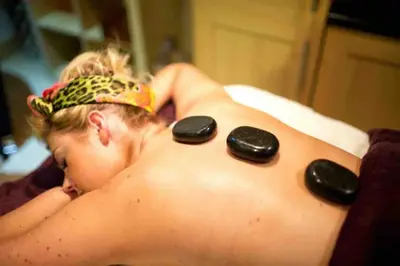 a man in a bathtub with three rocks on his back at Driftwood Lodge - South Lakeland Leisure Village in Carnforth