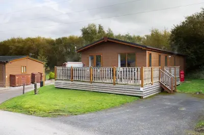 a log cabin with a porch and a house at Driftwood Lodge - South Lakeland Leisure Village in Carnforth