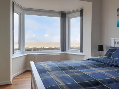 a bedroom with a bed and two large windows at Flat 1, Sandridge Court in Knott End-on-Sea