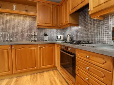 a kitchen with wooden cabinets and stainless steel appliances at Flat 1, Sandridge Court in Knott End-on-Sea
