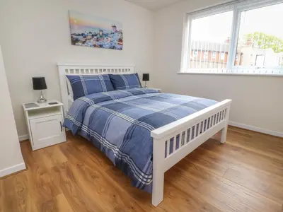 a bedroom with a bed with a blue and white comforter at Flat 1, Sandridge Court in Knott End-on-Sea