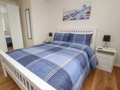 a bedroom with a blue and white bed and two tables at Flat 1, Sandridge Court in Knott End-on-Sea