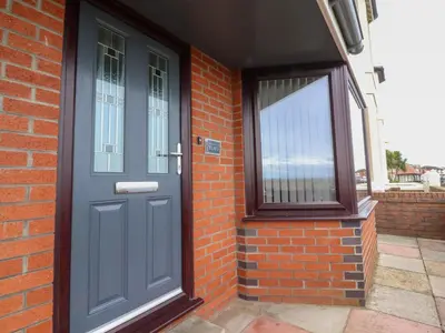 a blue door on a brick building with a window at Flat 1, Sandridge Court in Knott End-on-Sea