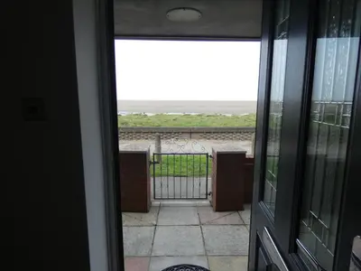 a door to a balcony with a view of the ocean at Flat 1, Sandridge Court in Knott End-on-Sea