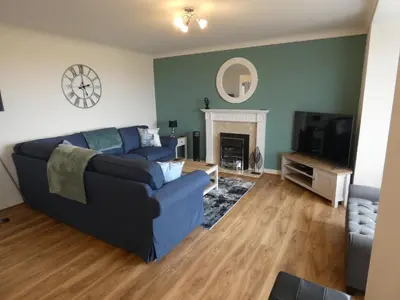 a living room with a blue couch and a tv at Flat 1, Sandridge Court in Knott End-on-Sea