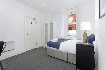 a white bedroom with a bed and a lamp at The Wavertree Rooms - Air Host & Stay - 6 Bedrooms in Liverpool