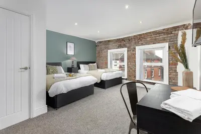 a bedroom with two beds and a brick wall at The Wavertree Rooms - Air Host & Stay - 6 Bedrooms in Liverpool