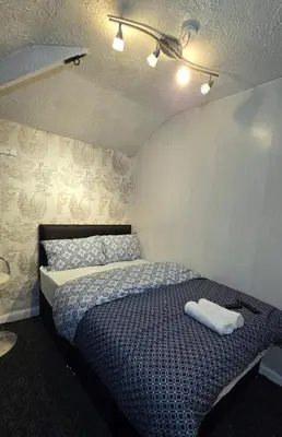 a bedroom with a bed with two towels on it at Ritchie Guest House in Wigan