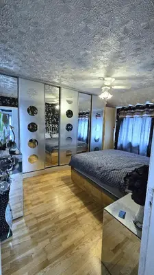 a bedroom with a bed and a wall with wine shelves at Ritchie Guest House in Wigan
