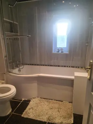 a bathroom with a tub and a toilet and a window at Ritchie Guest House in Wigan