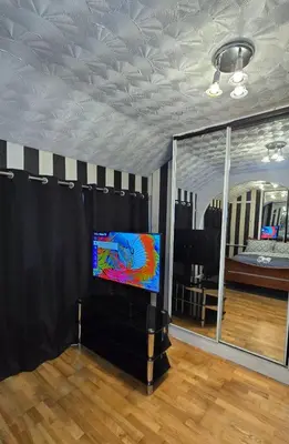 a living room with a tv and a mirror at Ritchie Guest House in Wigan