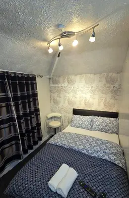 a bedroom with a bed with two towels on it at Ritchie Guest House in Wigan