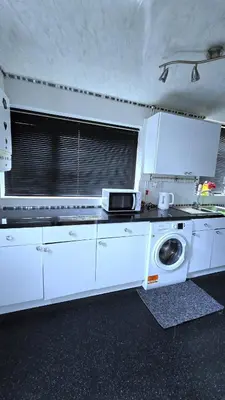 a kitchen with white cabinets and a washing machine at Ritchie Guest House in Wigan