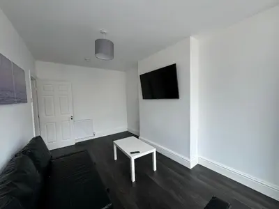 a living room with a couch and a tv on a wall at Theo apartment 150 meters from the winter gardens large groups welcome in Blackpool
