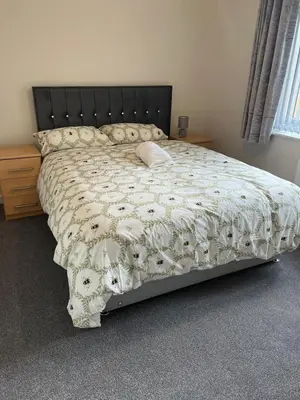 a bed with a white comforter with a pillow on it at Mesnes Place in Wigan