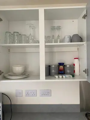 a kitchen shelf with dishes and glassware on it at Mesnes Place in Wigan